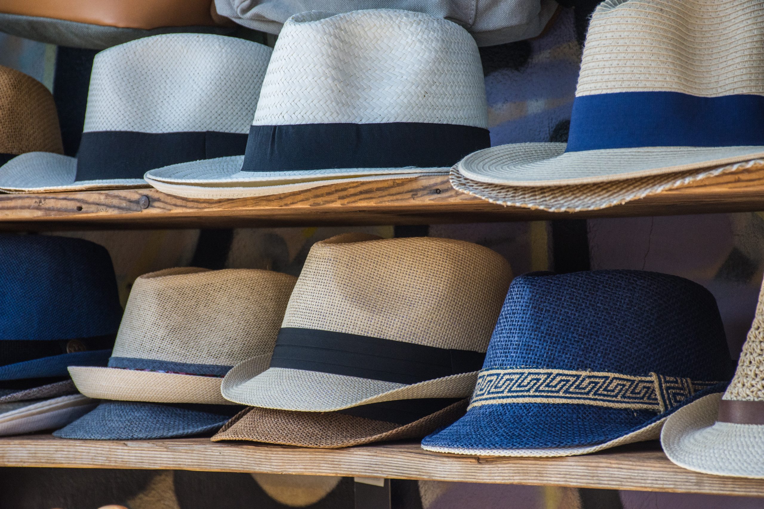 two wooden shelves lined with various fedoras. Photo by Héctor J. Rivas via Unsplash.com